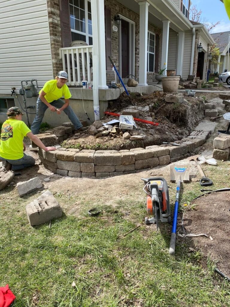 Contractor building a stone retaining wall in a Saint Louis backyard.