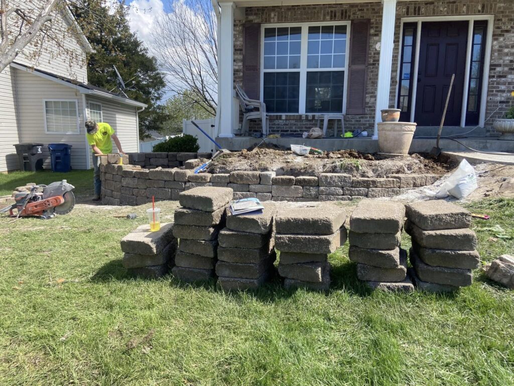 Contractor building a stone retaining wall in a Saint Louis backyard.